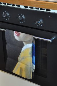 Theedoek Meisje met de Parel van Johannes Vermeer aan het handvat van de oven. 