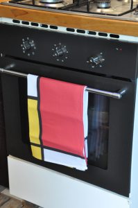 Theedoek met schilderij van Mondriaan aan het handvat van de oven.